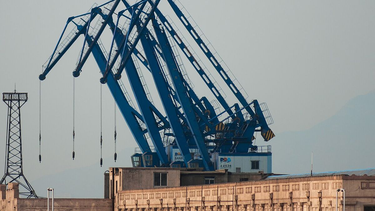 Blue harbour crane booms above a quay building in Dalian harbour