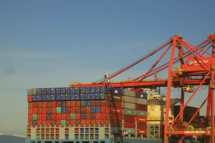 Container ship being unloaded under red gantry cranes in Vancouver