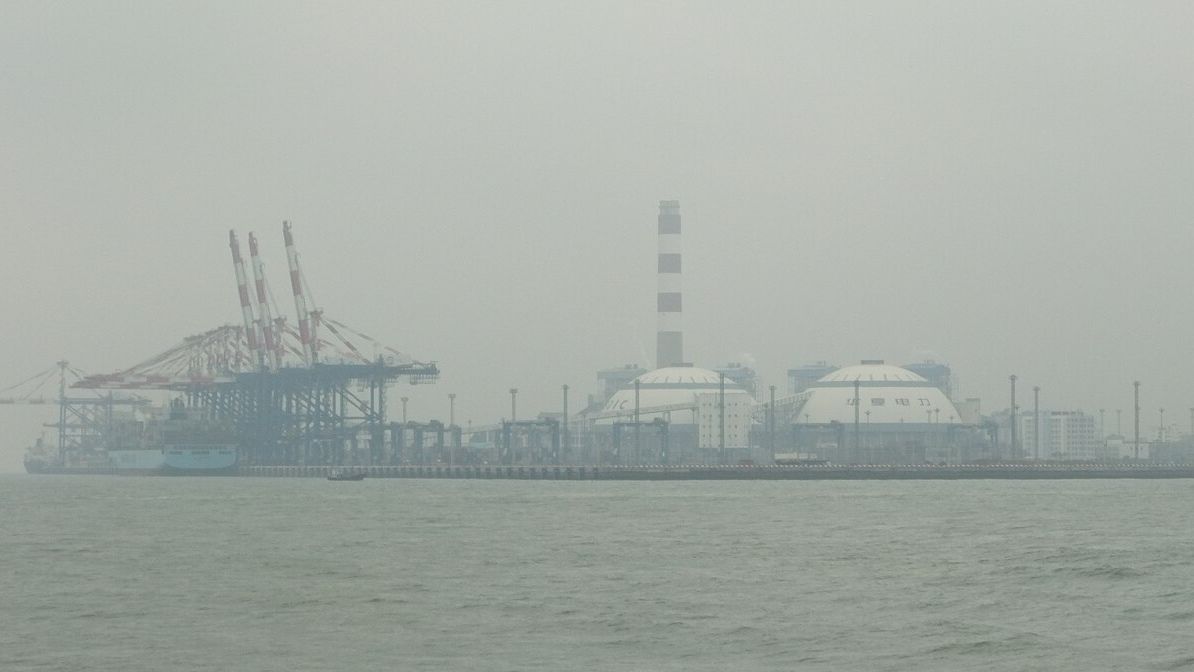 Container cranes at port facilities in Haicang, Xiamen, seen across the water on a hazy day